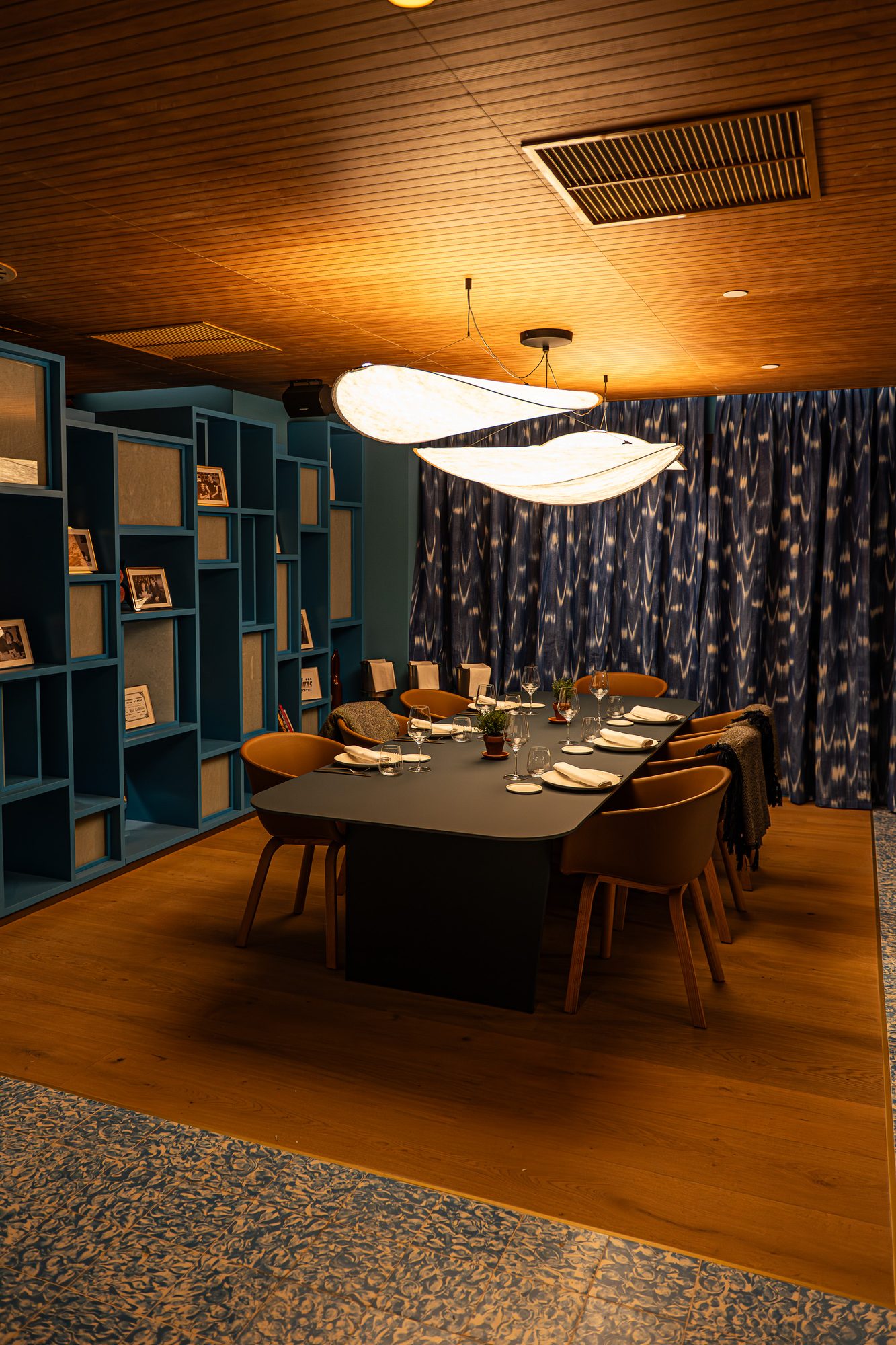 Comedor privado de Cañitas Málaga con mesa vestida, estanterías azules y lámparas suspendidas