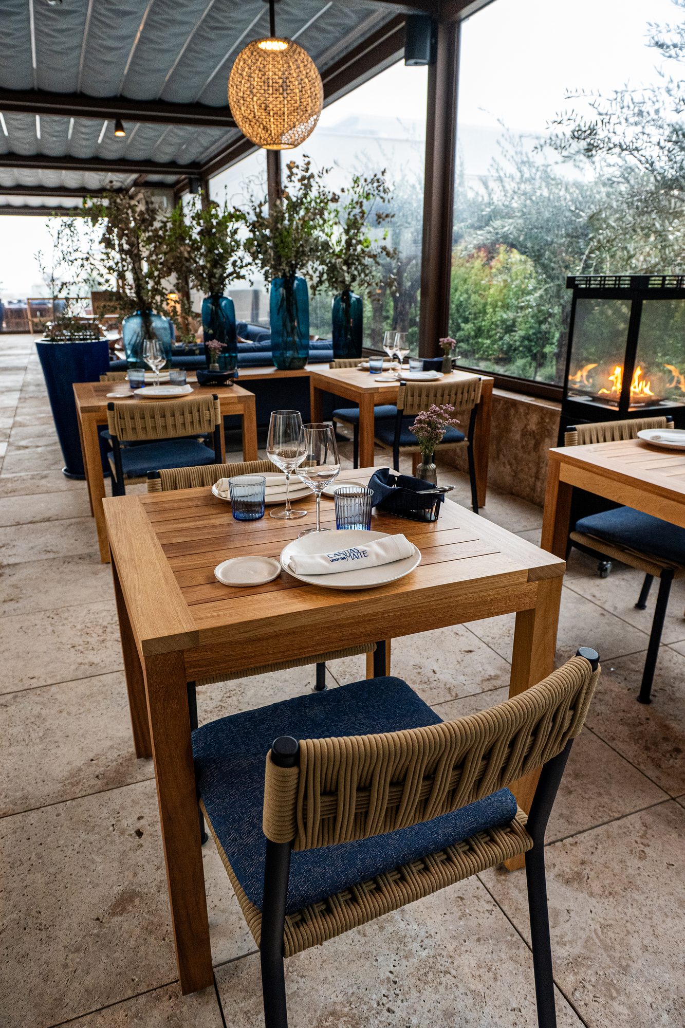 Terraza acristalada de Cañitas Málaga con olivos y mesas de madera en la última planta del hotel